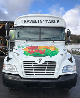 White bus with brightly-colored fruits and vegetables on it. 